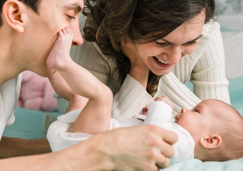 Vater und Mutter lächeln neugeborenes Baby an