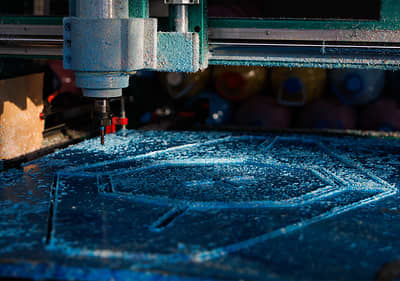 CNC машина изрязва сложен дизайн върху син материал