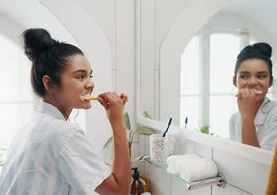 Жена мие зъбите си пред огледало в баня