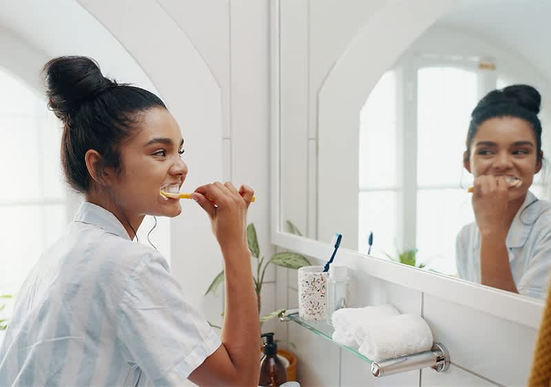 Жена мие зъбите си пред огледало в баня