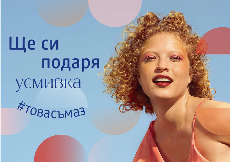Жена с къдрава коса и розова рокля на фона на синьо небе