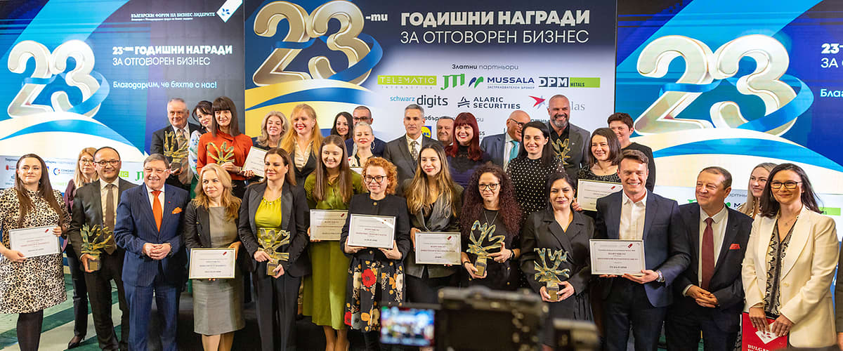 Две жени държат сертификат на събитие с банер на заден план.
