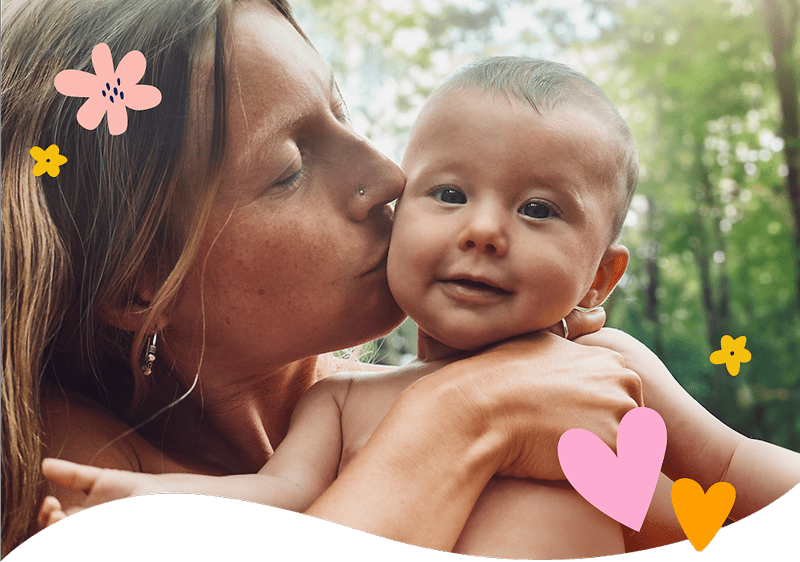 Mutter mit Baby im Freien umgeben von Pflanzen und Blumen