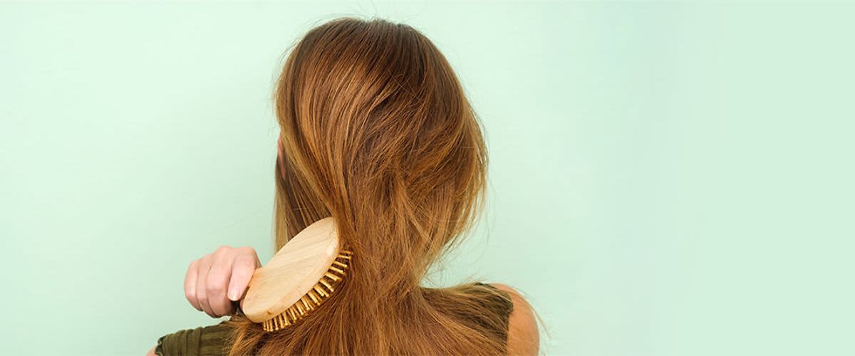 Žena popravlja svoju frizuru sa češljem