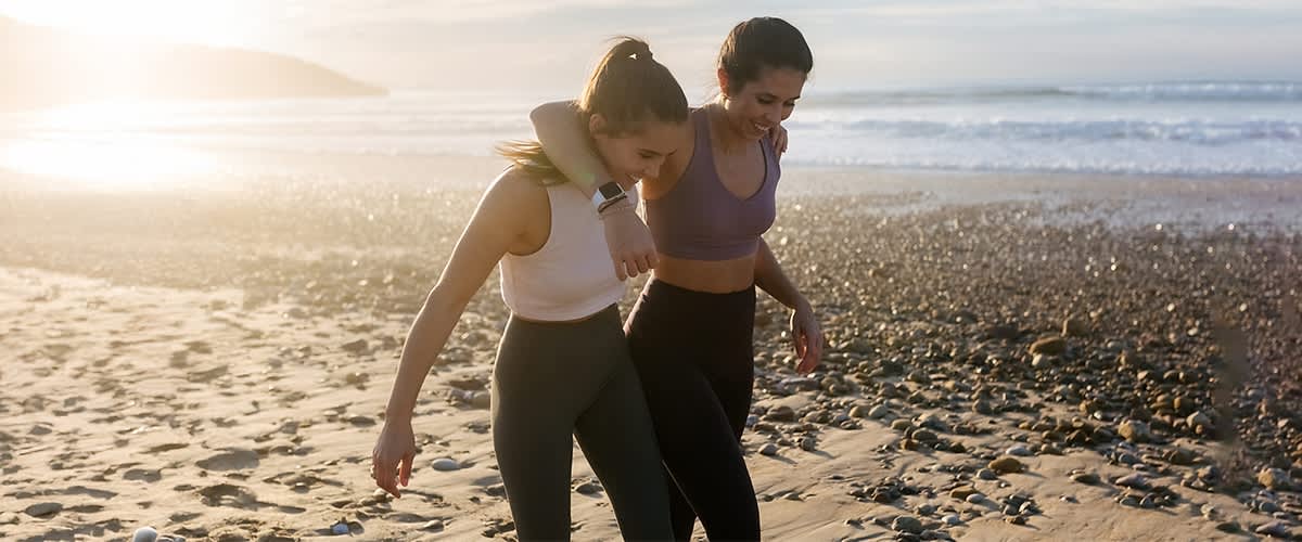 Dvije djevojke šeću zagrljene plažom