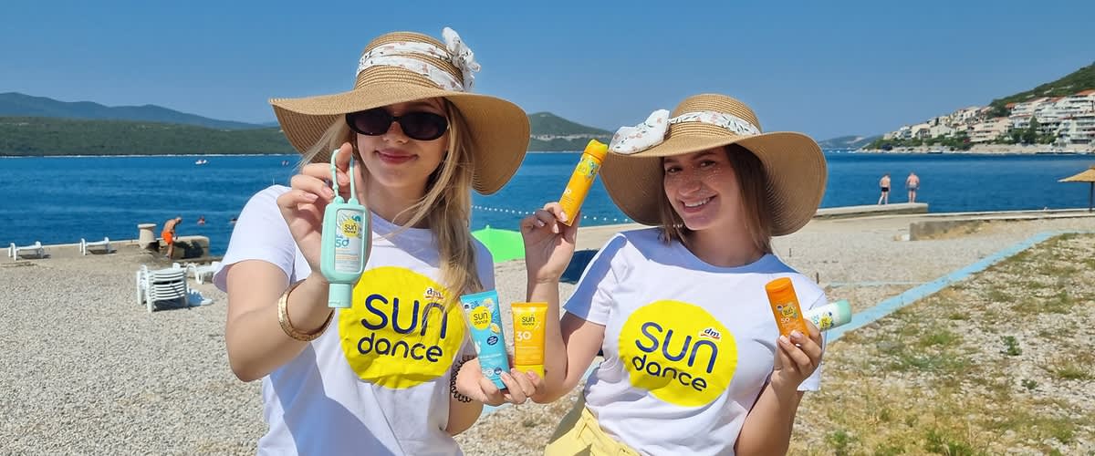 Dvije djevojke na plaži sa šeširima i SUNDANCE kremama za sunčanje