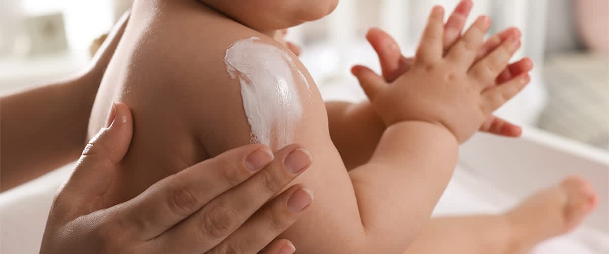 Mazanje bebe kremom za njegu