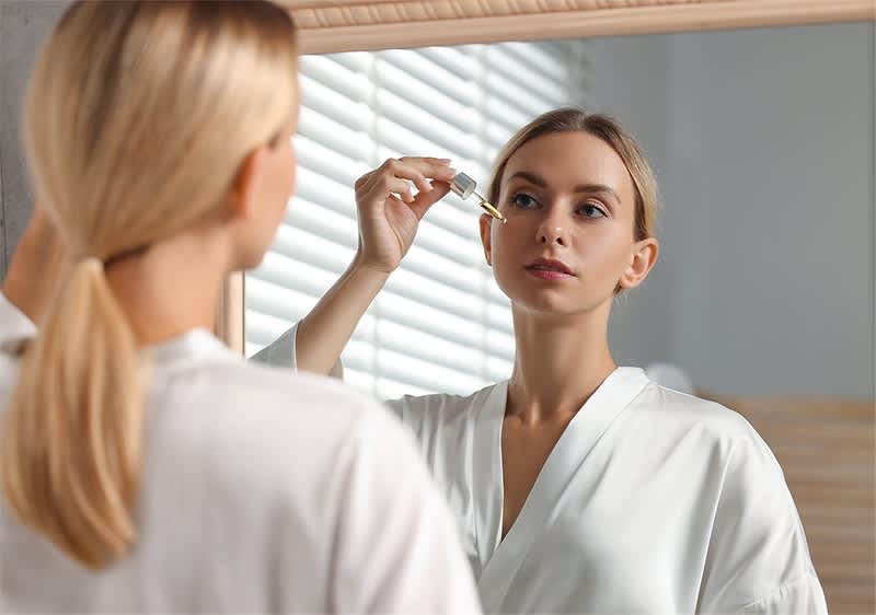 Žena nanosi serum na lice