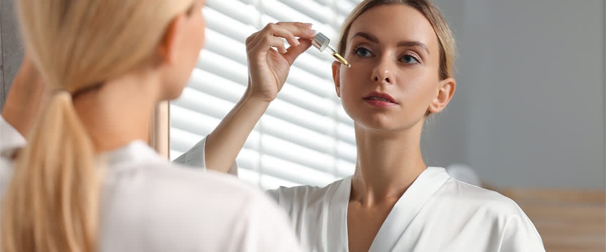 Žena nanosi serum na lice