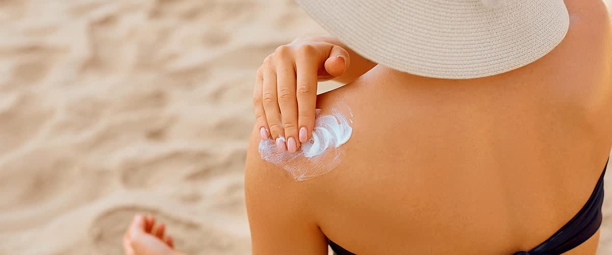 Žena na plaži nanosi kremu za zaštitu od sunca