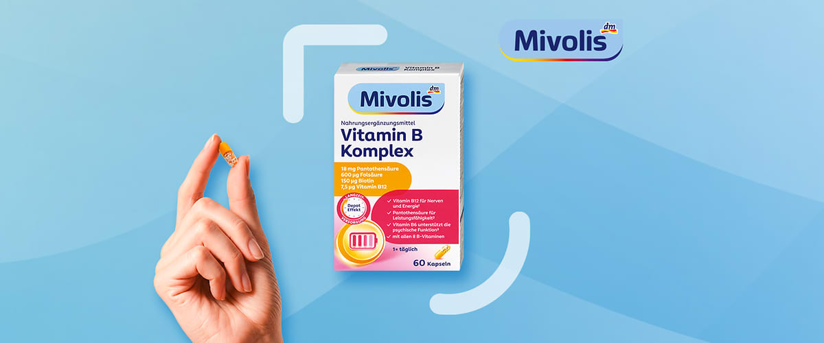 Vitamin B Komplex kapsule u ruci i kutija proizvoda Mivolis na plavoj pozadini