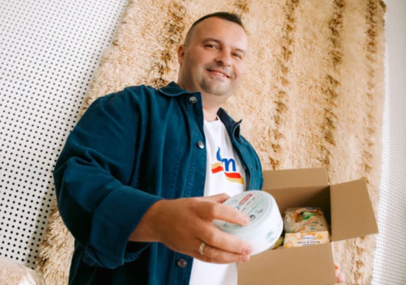 Muškarac s kutijom namirnica drži paket i posudu za hranu