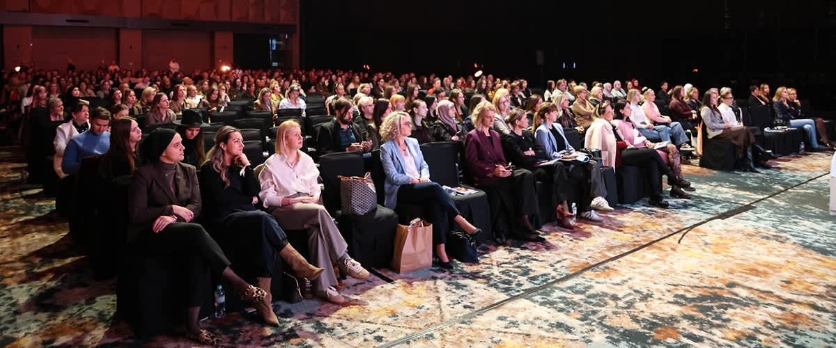Konferencija u velikoj dvorani s publikom sjedećom i osvijetljenim stropom