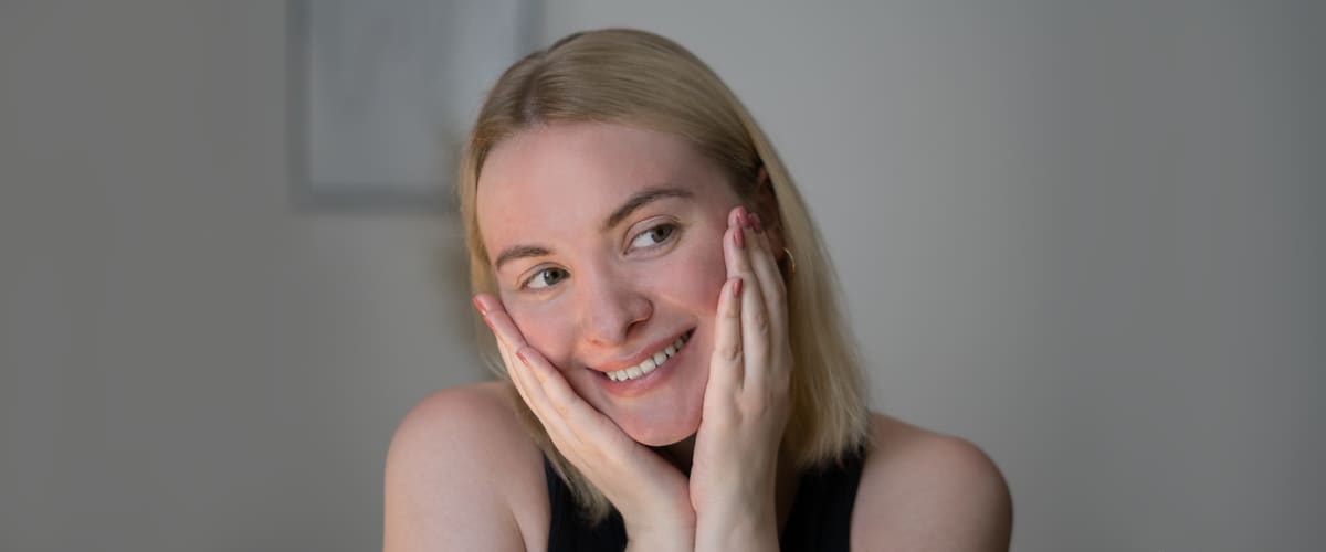 Portret nasmijane žene s rukama na licu
