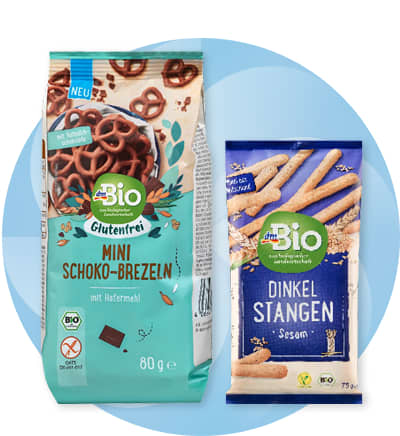 Obrázek: Dva balíčky dmBio produktů, mini čoko preclíky a špaldové tyčinky se sezamem.