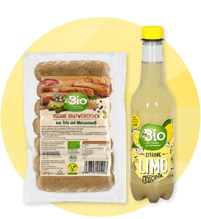 Balení veganských klobás a láhev citronové limonády na žlutém pozadí
