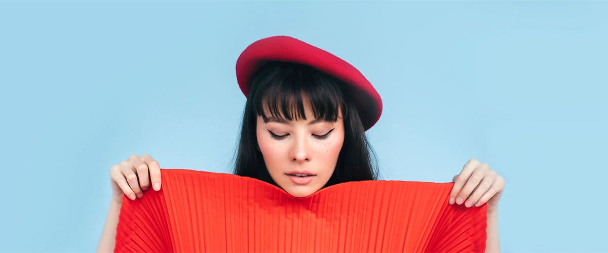 Žena s červeným baretem a červeným plisovaným oděvem