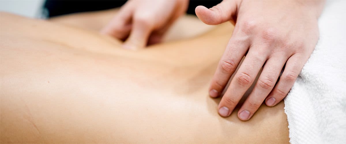 Masáž zad rukama na bílém ručníku