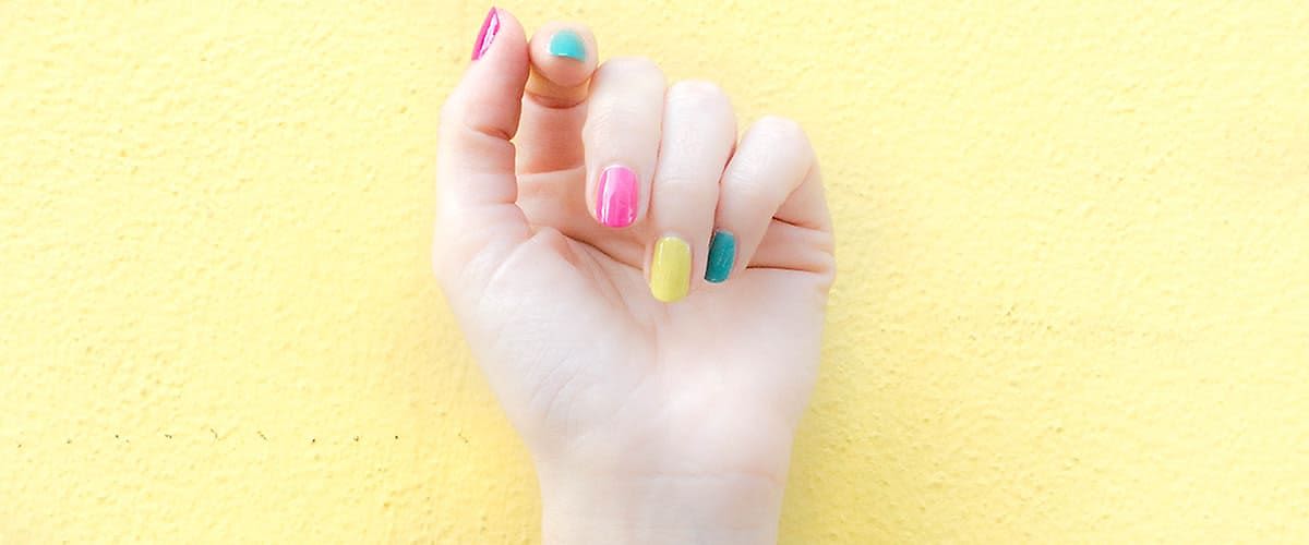 Ruka s pestrobarevně nalakovanými nehty