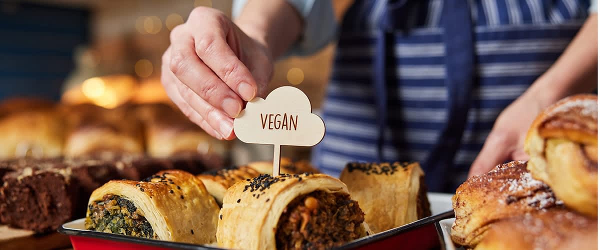 Pečivo s náplní označené cedulkou vegan na pultu v pekárně