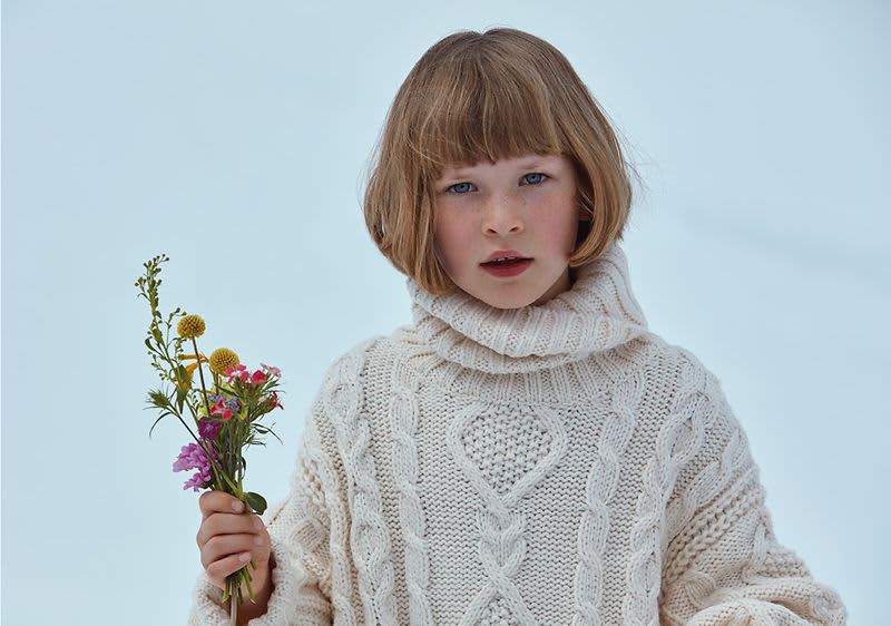 Dítě v pleteném svetru držící květiny