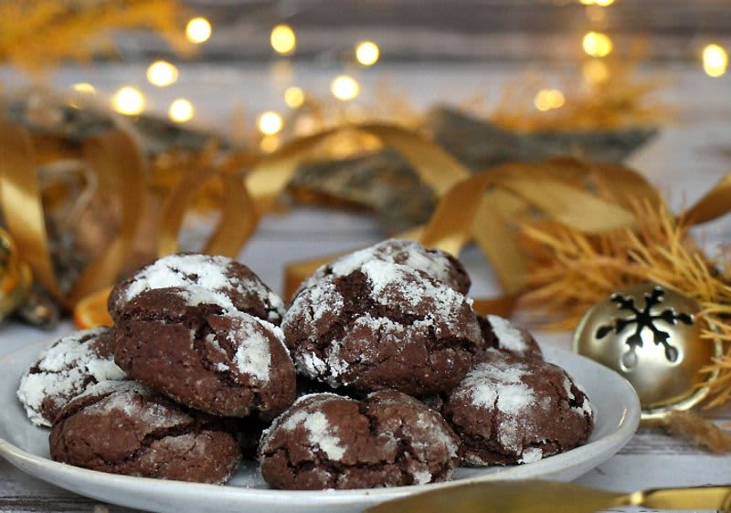 Čokoládové sušenky na talíři s vánoční dekorací a světýlky v pozadí