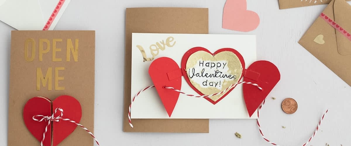 Valentýnské přání s nápisem Happy Valentine's day a červenými srdíčky na bílém a hnědém papíře