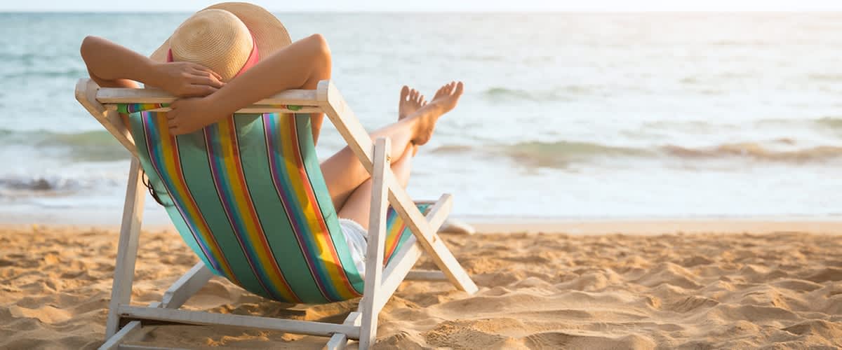 Žena v klobouku relaxuje na plážovém lehátku u moře