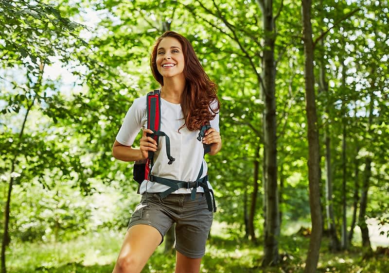 Žena s batohem v lese během túry