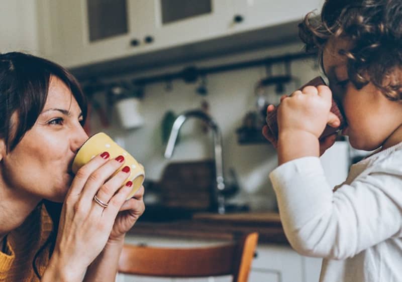 Dítě pije z hrnku v kuchyni