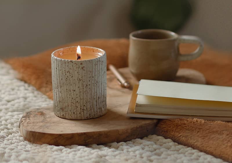 Kniha, svíčka a šálek leží na posteli