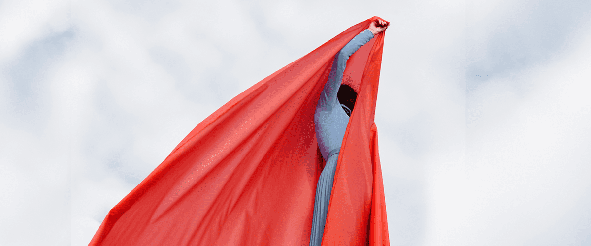 Osoba držící velkou červenou látku proti obloze