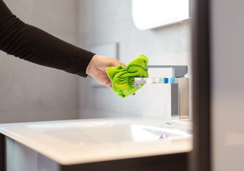 Čištění koupelnového kohoutku zeleným hadříkem