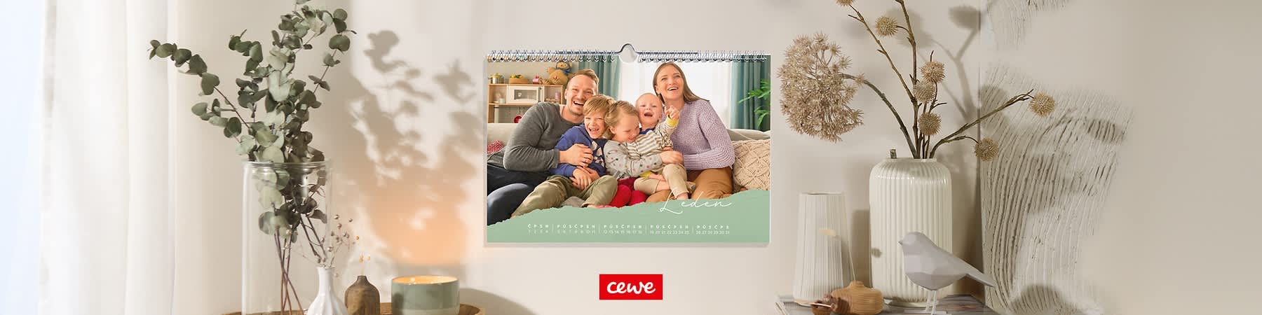 Rodinná fotografie na kalendáři, lidé sedí na pohovce, svíčka a rostlina na stole.