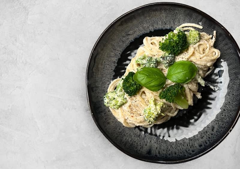Těstoviny s brokolicí a bazalkou na černém talíři