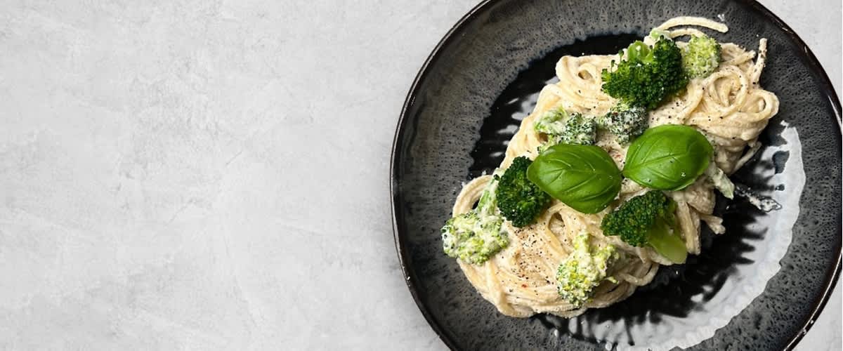 Těstoviny s brokolicí a bazalkou na černém talíři