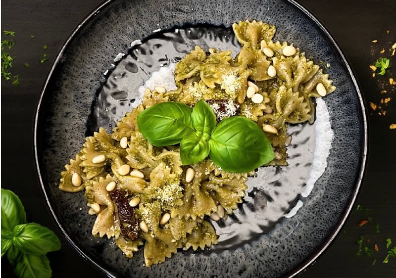Těstoviny s pestem, piniovými oříšky a bazalkou na tmavém talíři