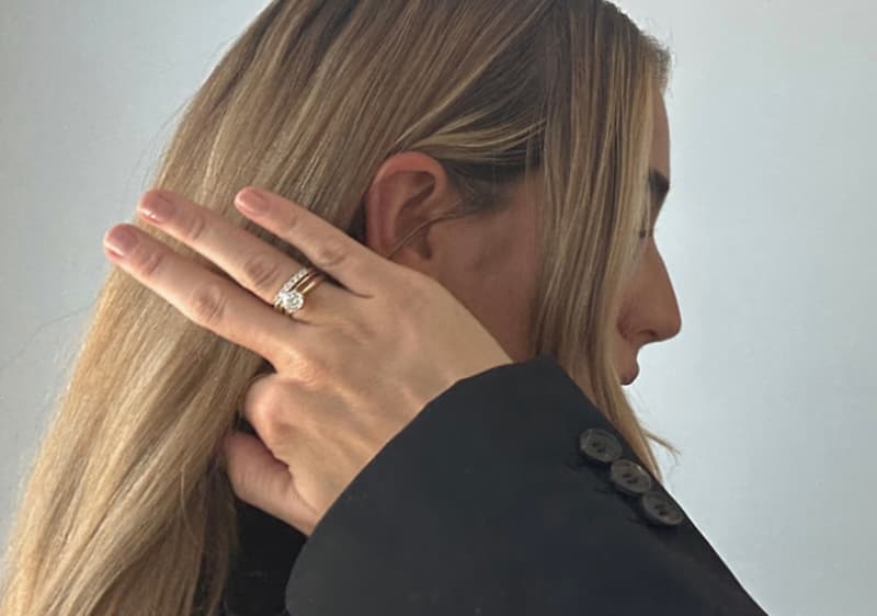 Žena s dlouhými blond vlasy ukazuje prsten na ruce