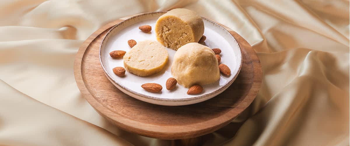Marcipánové kuličky na talíři s mandlemi na dřevěném podnosu, pozadí z jemné látky