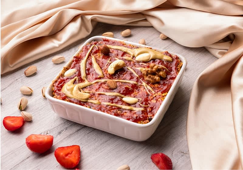 Dezert s jahodami, ořechy a krémem na dřevěném stole s látkou v pozadí