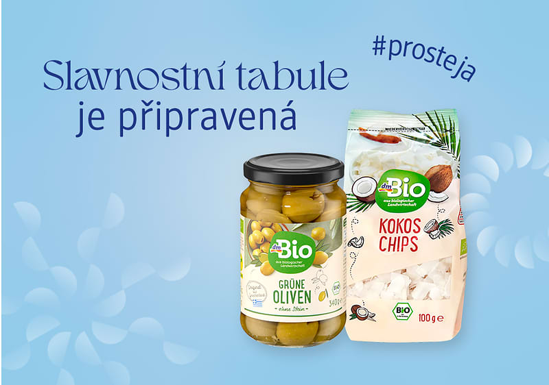 Sklenice zelených oliv a balení kokosových chipsů na modrém pozadí s textem Slavnostní tabule je připravená