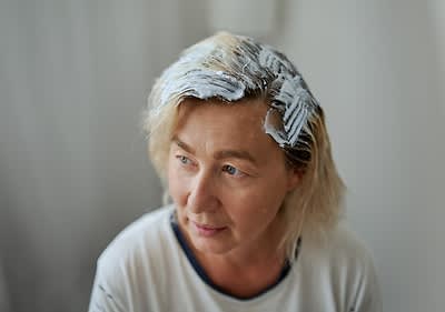 Osoba s blond vlasy, na které je nanesena bílá barva nebo melírovací směs