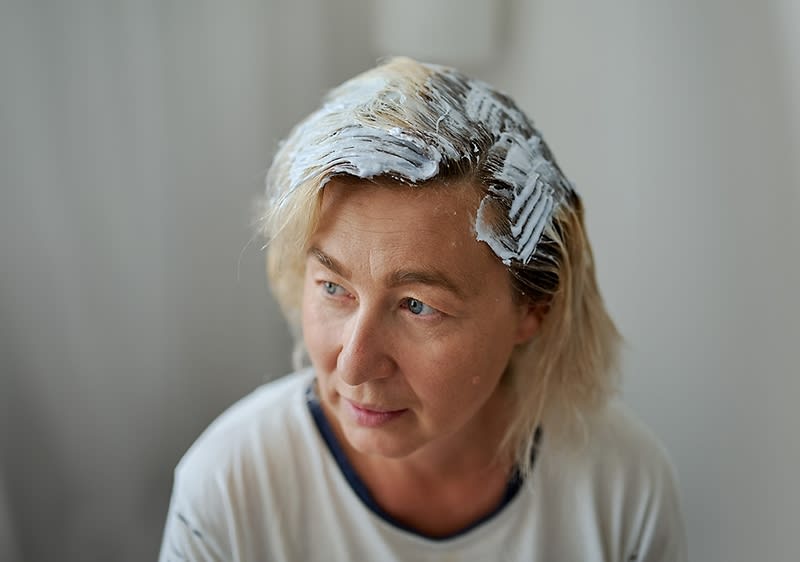 Osoba s blond vlasy, na které je nanesena bílá barva nebo melírovací směs