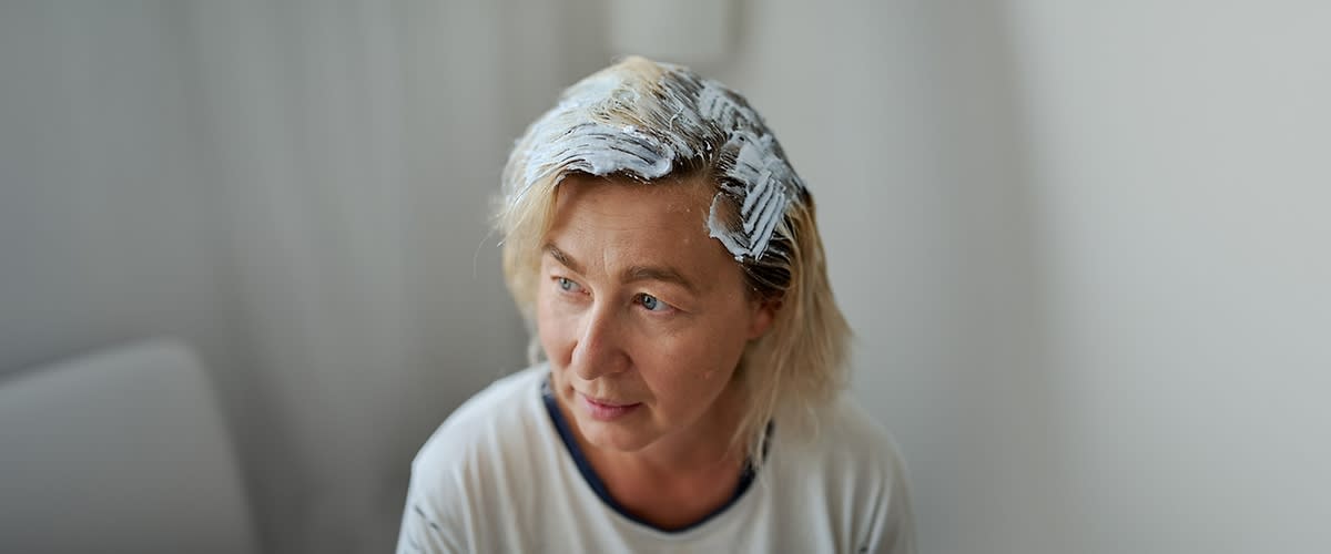 Osoba s blond vlasy, na které je nanesena bílá barva nebo melírovací směs