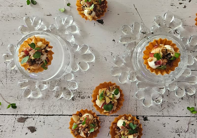 Malé koláčky s ořechy a bylinkami na skleněných talířcích na dřevěném stole