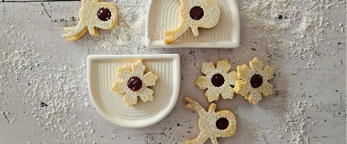 Sušenky s marmeládou na talířích posypané moučkovým cukrem