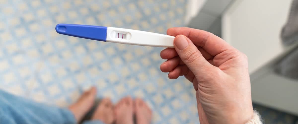 Těhotenský test s pozitivním výsledkem držený v ruce