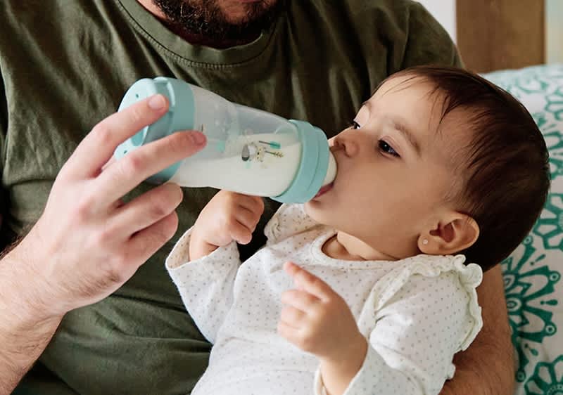 otec krmí dítě mlékem z láhve