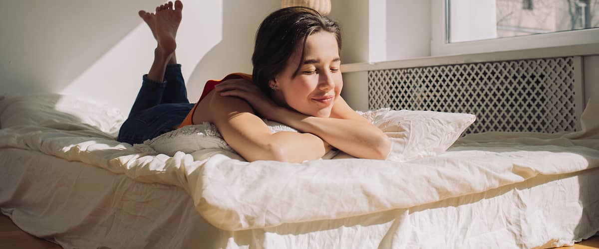 Žena ležící na posteli v slunečním světle