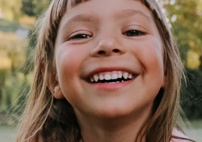 usmívající se dívka s přírodou v pozadí